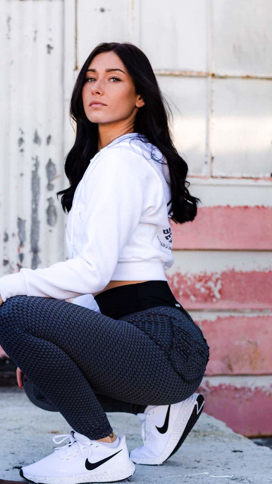 A woman squatting in a pair of Curve X Leggings in Hex Black. 